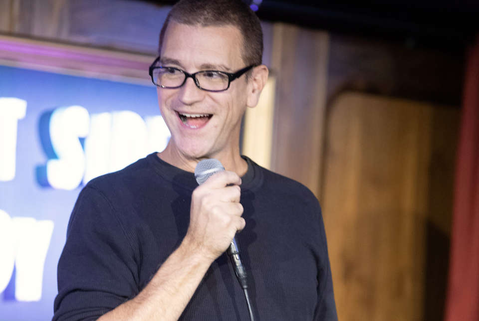 Clayton Fletcher telling jokes at a comedy show.